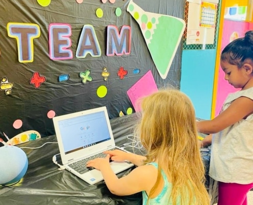 two kids making art with colored cut-outs on a table