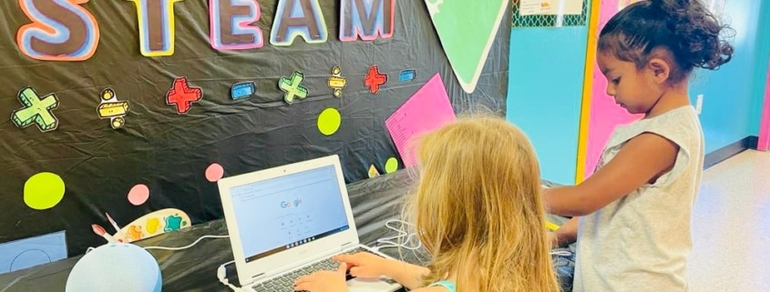 two kids making art with colored cut-outs on a table
