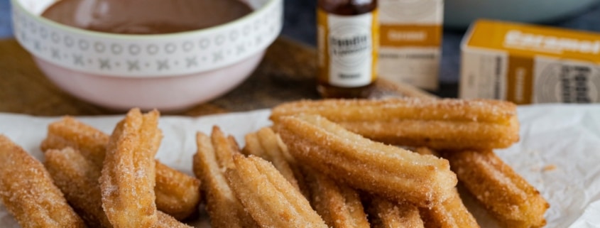 Churros on a paper towel and chocolate sauce on the side