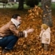 man and baby playing with autumn leaves Thanksgiving