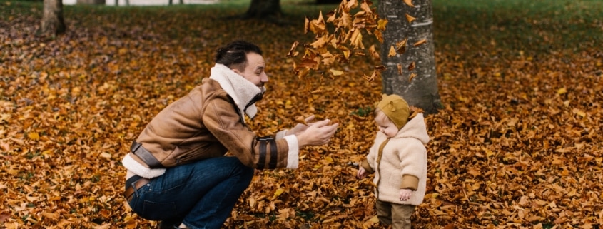 man and baby playing with autumn leaves Thanksgiving