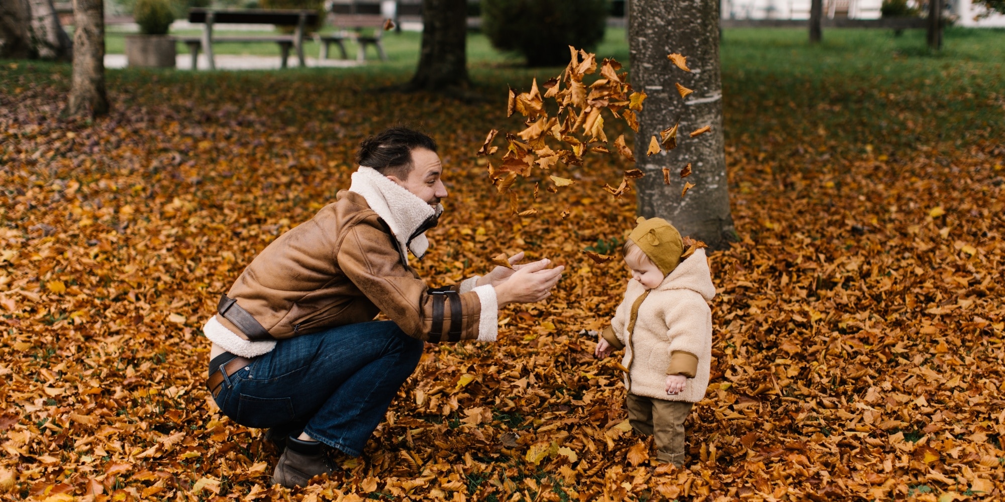 man and baby playing with autumn leaves Thanksgiving