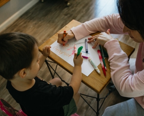 little boy coloring with his mom