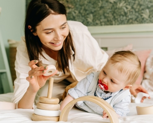 mother playing wooden toy with her baby