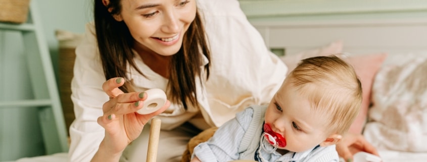 mother playing wooden toy with her baby