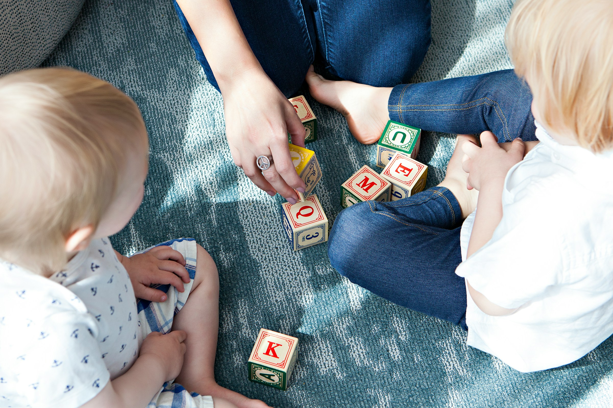 A close-up shot of a parent and their children playing with letter blocks