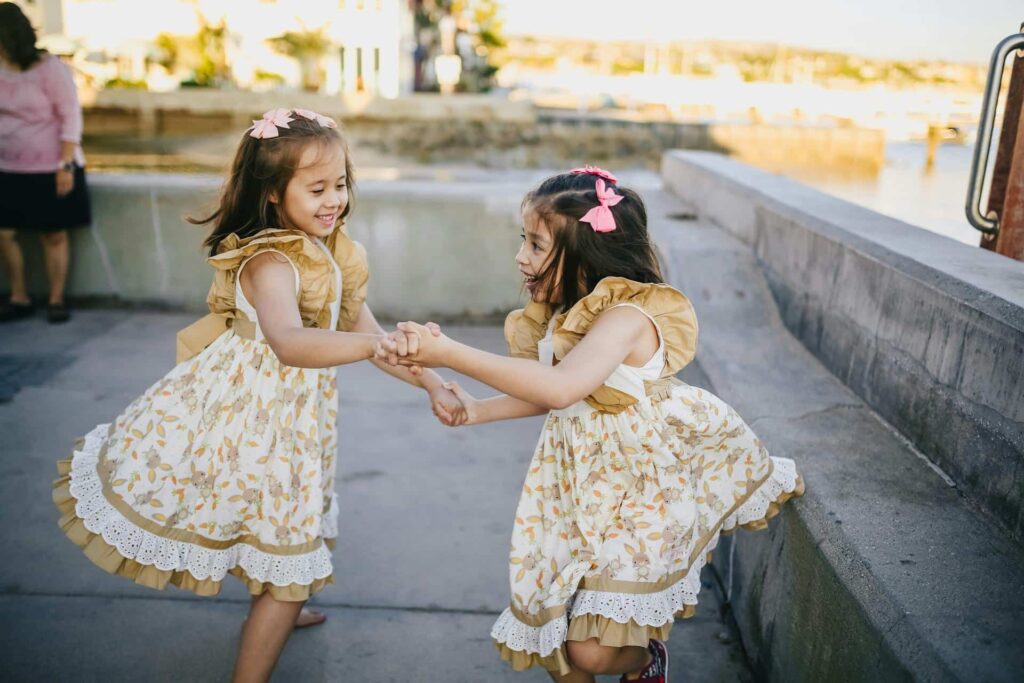 Two Young Girls in White Floral Dress Dancing on the Street